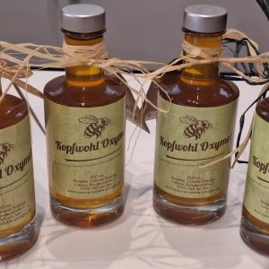 Handgemachte Flaschen mit Kopfwohl Oxymel, dekoriert mit Naturfasern und Etiketten.